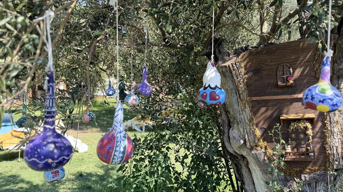 Zeytin ağacındaki el işi süsler ve küçük ahşap ev